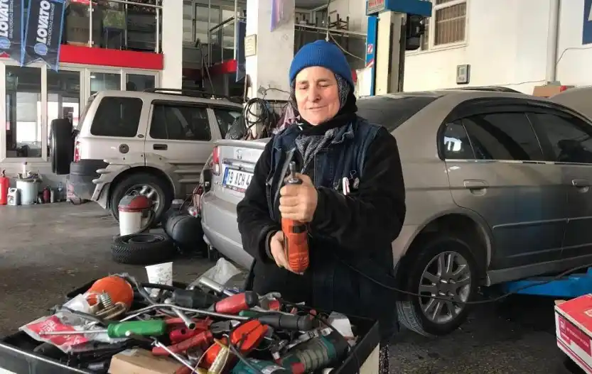 Oto sanayide elinde matkapla gülümseyen usta kadın